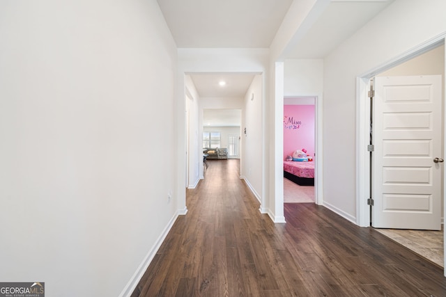 hallway featuring dark wood-style floors and baseboards