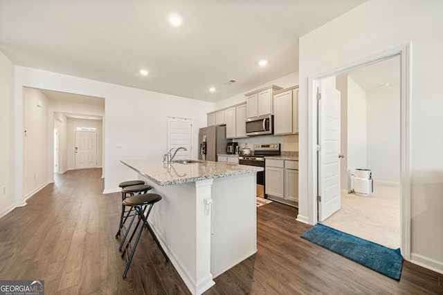 2030 Vidalia Ct, Dacula, GA 30019 - kitchen with appliances with stainless steel finishes, an island with sink, a kitchen bar, dark wood finished floors, and a sink