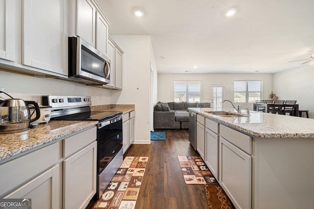 2030 Vidalia Ct, Dacula, GA 30019 - kitchen with stainless steel appliances, a sink, open floor plan, dark wood-style floors, and an island with sink