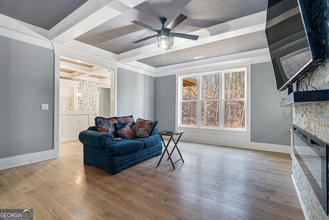 living area featuring beam ceiling, ornamental molding, a fireplace, and wood finished floors