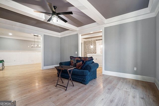 living area with baseboards, beamed ceiling, ornamental molding, wood finished floors, and a ceiling fan