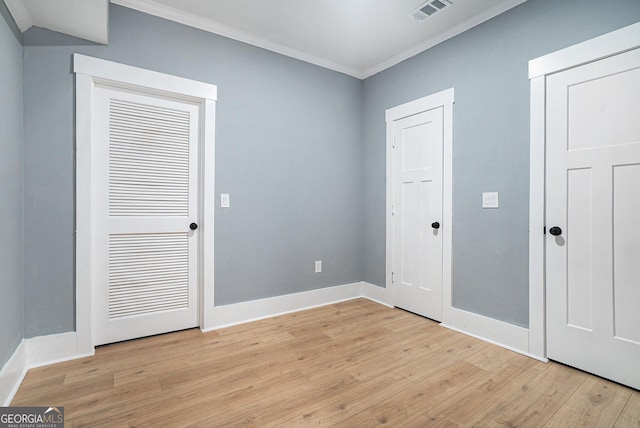 unfurnished bedroom with light wood finished floors, visible vents, baseboards, and ornamental molding