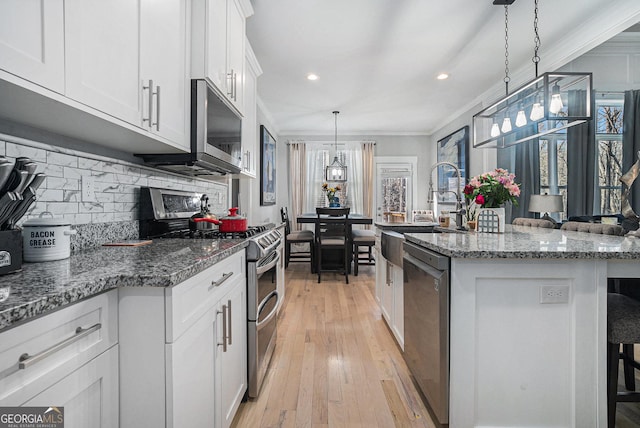 kitchen featuring a breakfast bar area, plenty of natural light, stainless steel appliances, white cabinetry, and crown molding