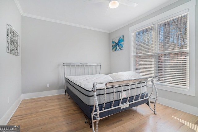 bedroom with baseboards, multiple windows, wood finished floors, and crown molding