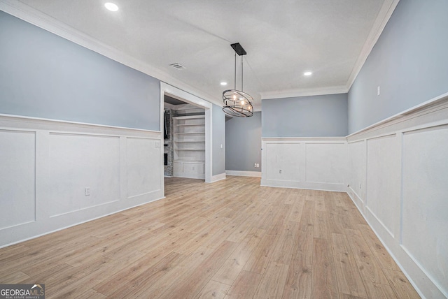 unfurnished dining area featuring wood finished floors, recessed lighting, ornamental molding, wainscoting, and a decorative wall