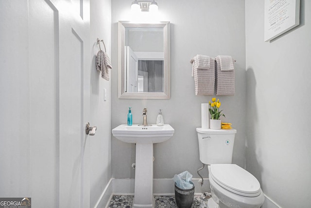 half bathroom with baseboards and toilet