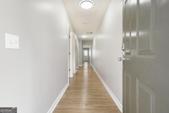 hallway featuring light wood-type flooring and baseboards