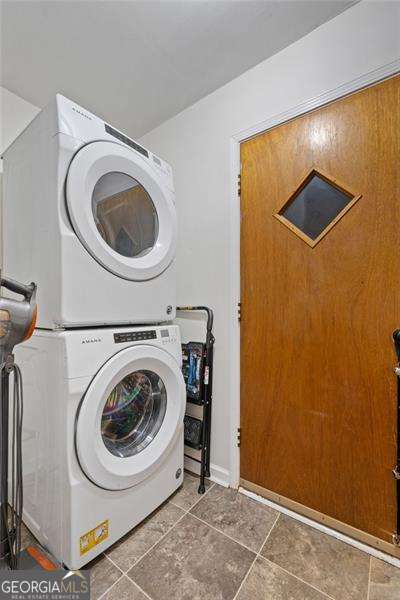 laundry area with laundry area, stacked washing maching and dryer, and tile patterned floors