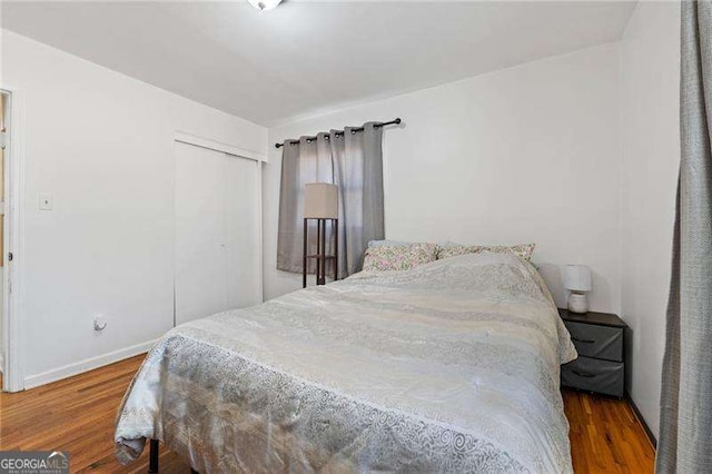 bedroom featuring a closet, wood finished floors, and baseboards