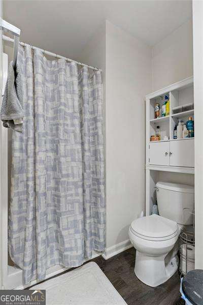 full bathroom featuring a shower with curtain, baseboards, toilet, and wood finished floors