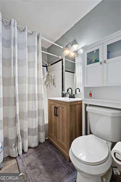 full bathroom with toilet, a shower with shower curtain, and vanity