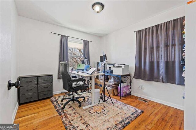 office featuring baseboards, visible vents, and wood finished floors