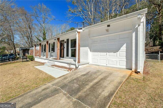 single story home featuring brick siding, concrete driveway, an attached garage, covered porch, and a front yard