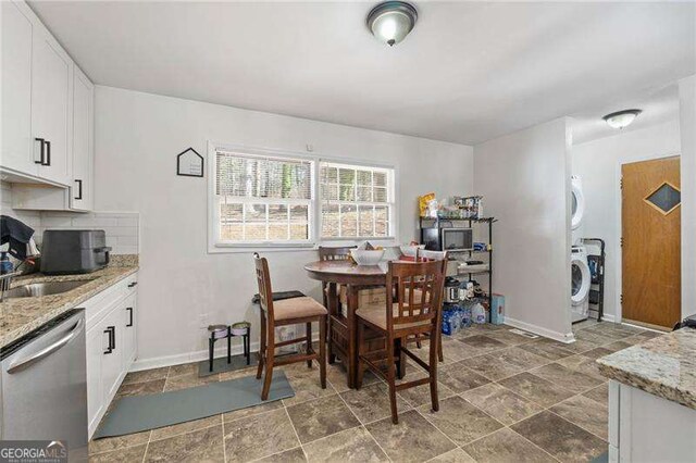 dining room featuring stone finish flooring, stacked washer / dryer, and baseboards