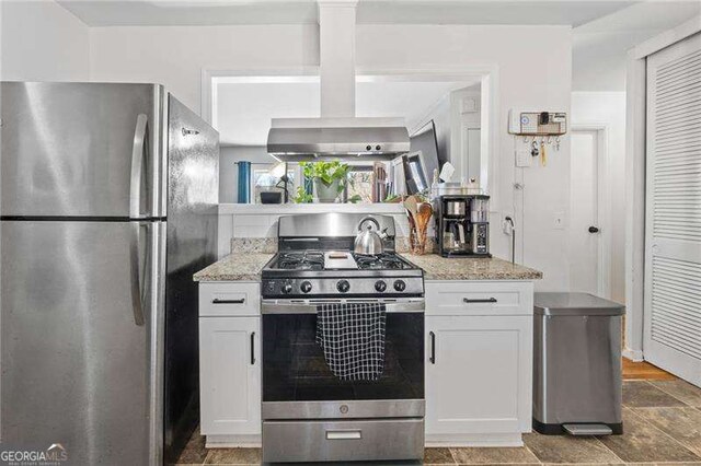 kitchen with appliances with stainless steel finishes, white cabinetry, and light stone countertops