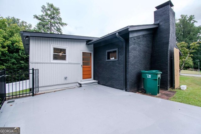 back of property featuring a patio area, brick siding, and a chimney