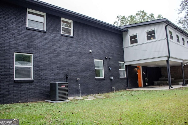 back of property featuring a patio area, a lawn, and brick siding