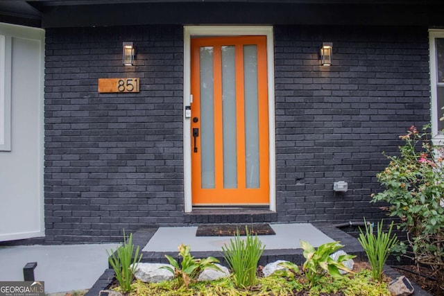 view of exterior entry featuring brick siding