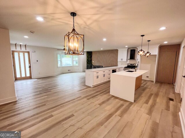 kitchen featuring open floor plan, stainless steel range oven, a center island with sink, and light wood finished floors