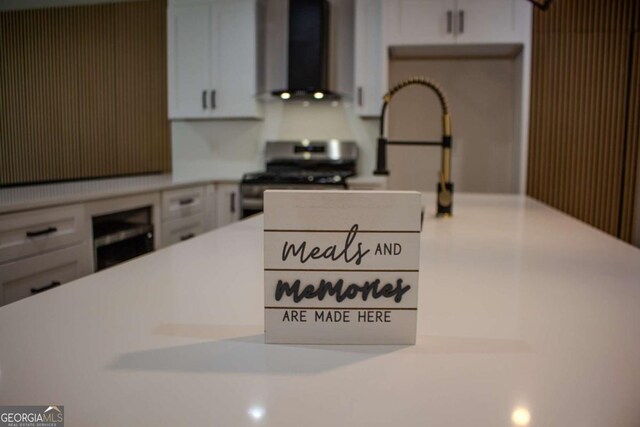 kitchen featuring stainless steel gas stove, wall chimney exhaust hood, and light countertops