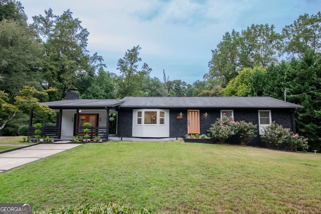 view of front of house with french doors, a front lawn, a chimney, and driveway