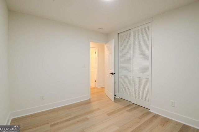 unfurnished bedroom with light wood finished floors, a closet, and baseboards