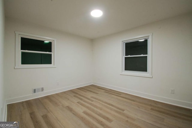 unfurnished room featuring visible vents, baseboards, and wood finished floors