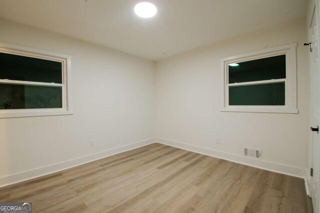 unfurnished room featuring visible vents, light wood-style flooring, and baseboards