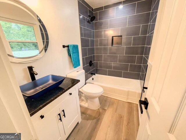 bathroom with toilet, shower / washtub combination, wood finished floors, and vanity