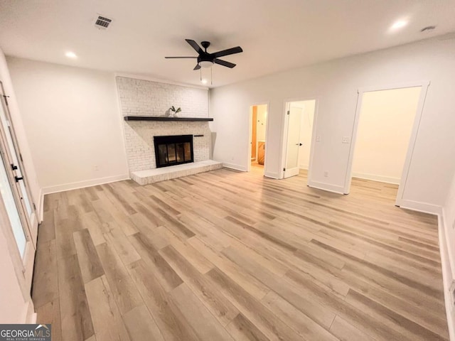 unfurnished living room featuring visible vents, baseboards, a ceiling fan, light wood-type flooring, and a brick fireplace