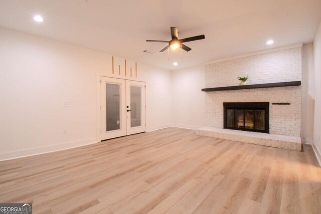 unfurnished living room featuring baseboards, a ceiling fan, wood finished floors, french doors, and a fireplace