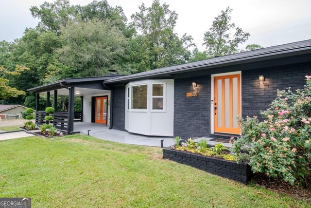 view of front of house featuring french doors, a front yard, and brick siding