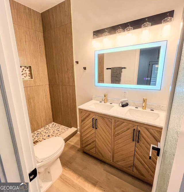 bathroom with double vanity, a sink, toilet, and wood finished floors