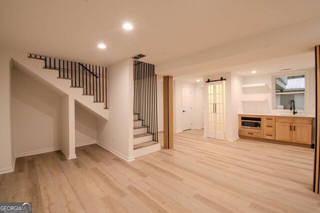 interior space featuring light wood finished floors, recessed lighting, a sink, baseboards, and stairs