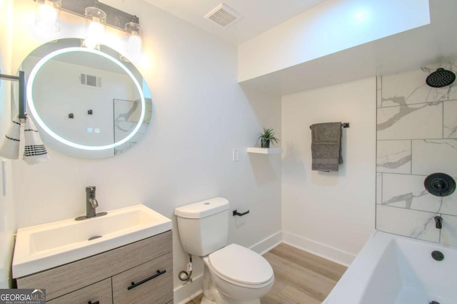 bathroom with visible vents, toilet, vanity, wood finished floors, and baseboards