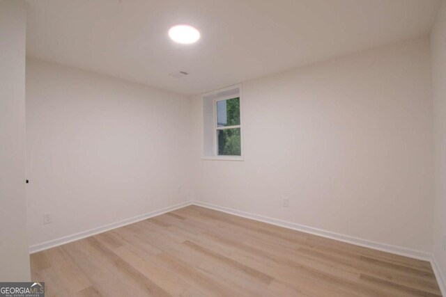 spare room with baseboards and light wood finished floors