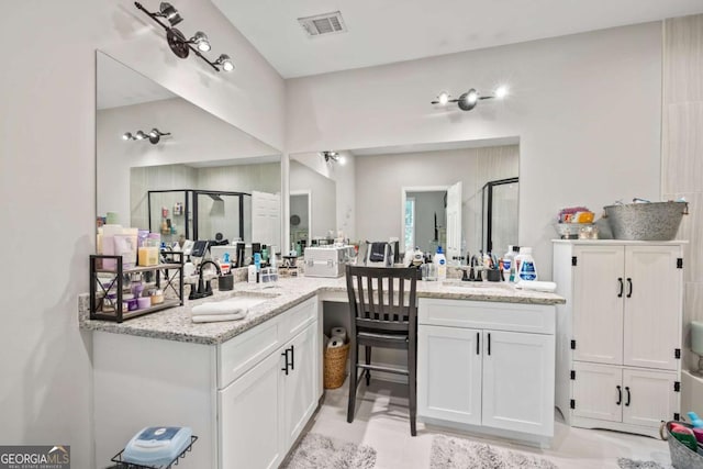 full bathroom featuring two vanities, a stall shower, visible vents, and a sink