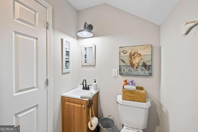 bathroom with lofted ceiling, vanity, and toilet