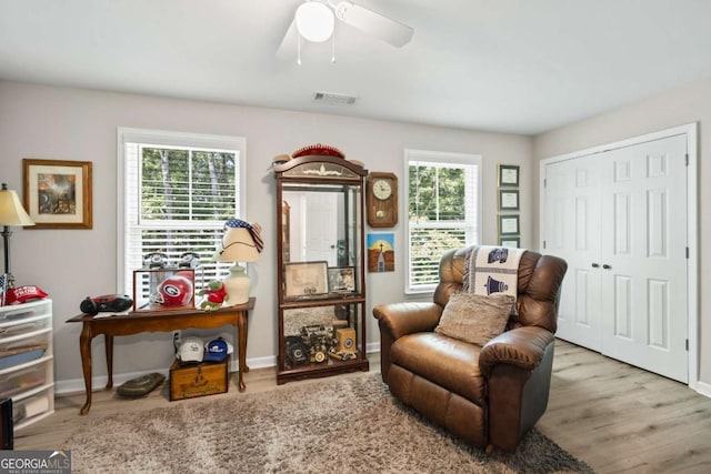 sitting room with baseboards, visible vents, ceiling fan, and wood finished floors