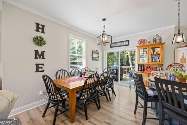 dining space with ornamental molding, light wood finished floors, a notable chandelier, and baseboards