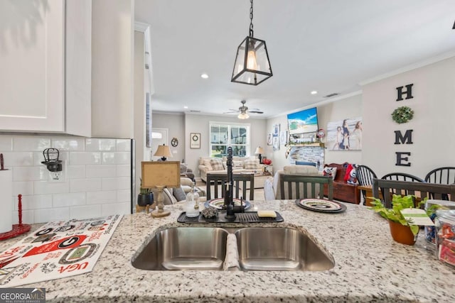 kitchen with ornamental molding, open floor plan, light stone counters, and tasteful backsplash