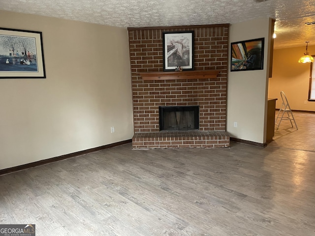 405415 Chase Dr, Fayetteville, GA 30214 - unfurnished living room featuring a textured ceiling, wood finished floors, and a brick fireplace
