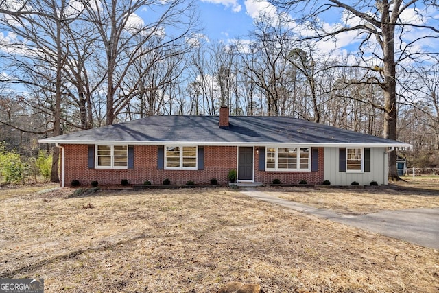 single story home featuring a chimney, board and batten siding, and brick siding