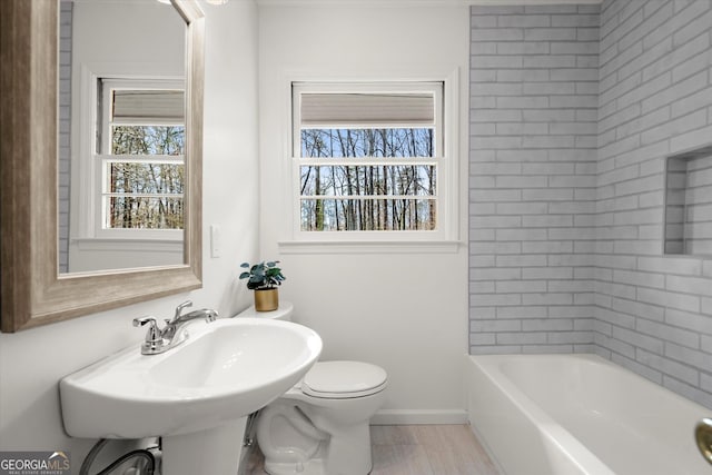 full bathroom with toilet, a sink, baseboards, and a wealth of natural light