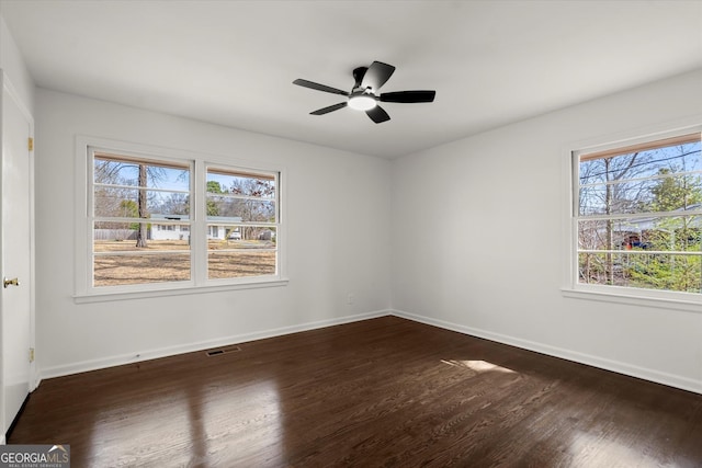 unfurnished room with dark wood-type flooring, visible vents, baseboards, and a ceiling fan