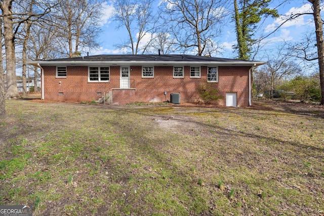 back of property with brick siding, crawl space, a lawn, and central air condition unit