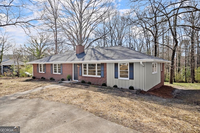 ranch-style home with board and batten siding, brick siding, and a chimney