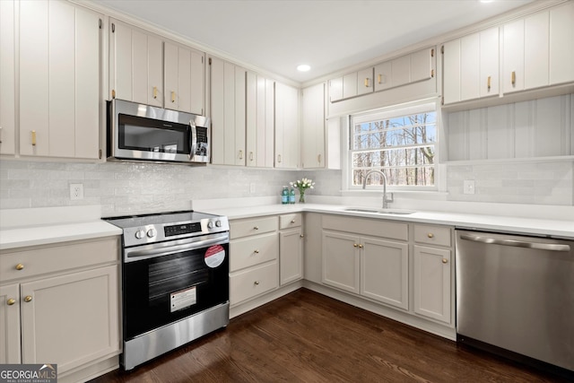 kitchen with tasteful backsplash, dark wood finished floors, appliances with stainless steel finishes, light countertops, and a sink