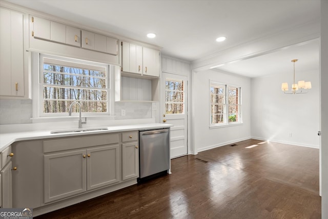 kitchen featuring dark wood-style floors, tasteful backsplash, stainless steel dishwasher, a sink, and baseboards