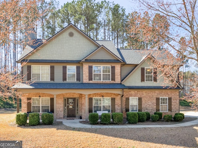 craftsman-style home with brick siding, a porch, and a shingled roof